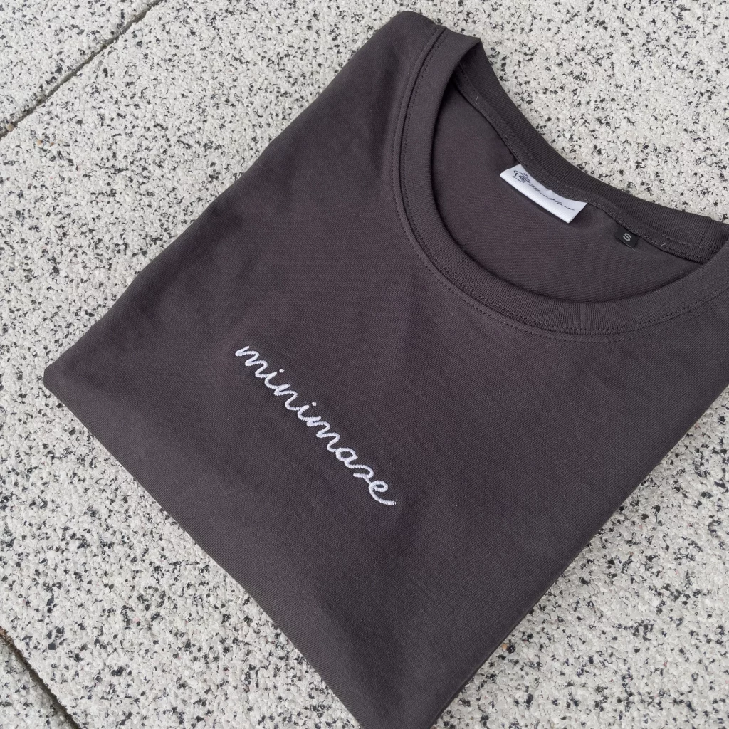 Grafitowy t-shirt marki minimaze z białym haftem logo 'minimaze' na klatce piersiowej. Wykonany z wysokiej jakości bawełny, idealny do casualowych stylizacji.